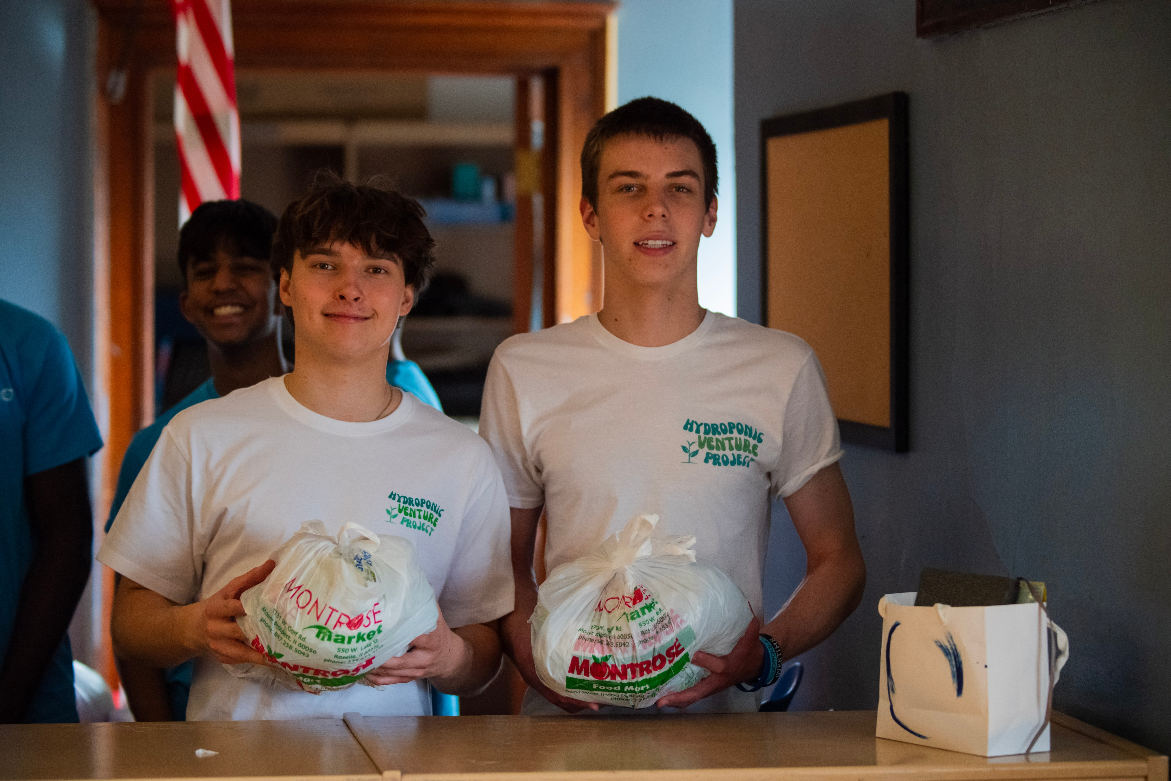 Two HVP volunteers holding fresh produce bags at a community distribution event.